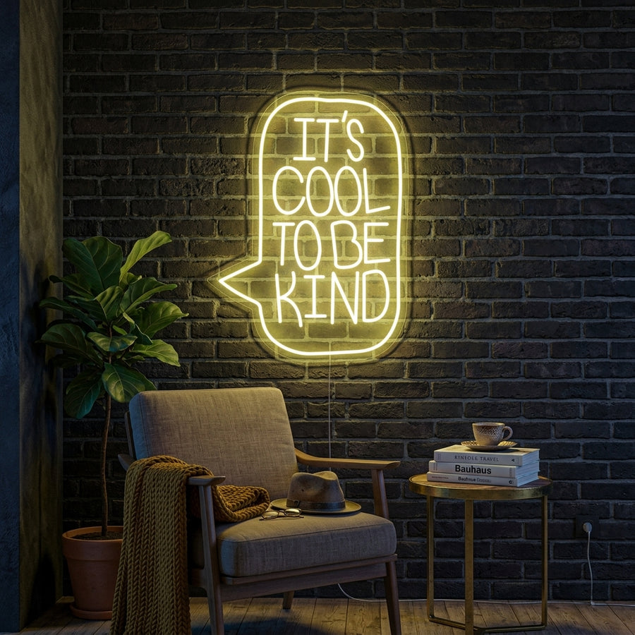 A cozy living room wall decorated with the glowing Its Cool To Be Kind neon sign