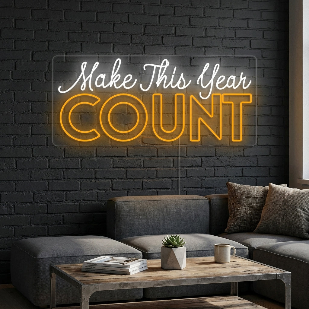 'Make This Year Count' motivational neon sign glowing warmly on a textured office wall, surrounded by plants and desk items.