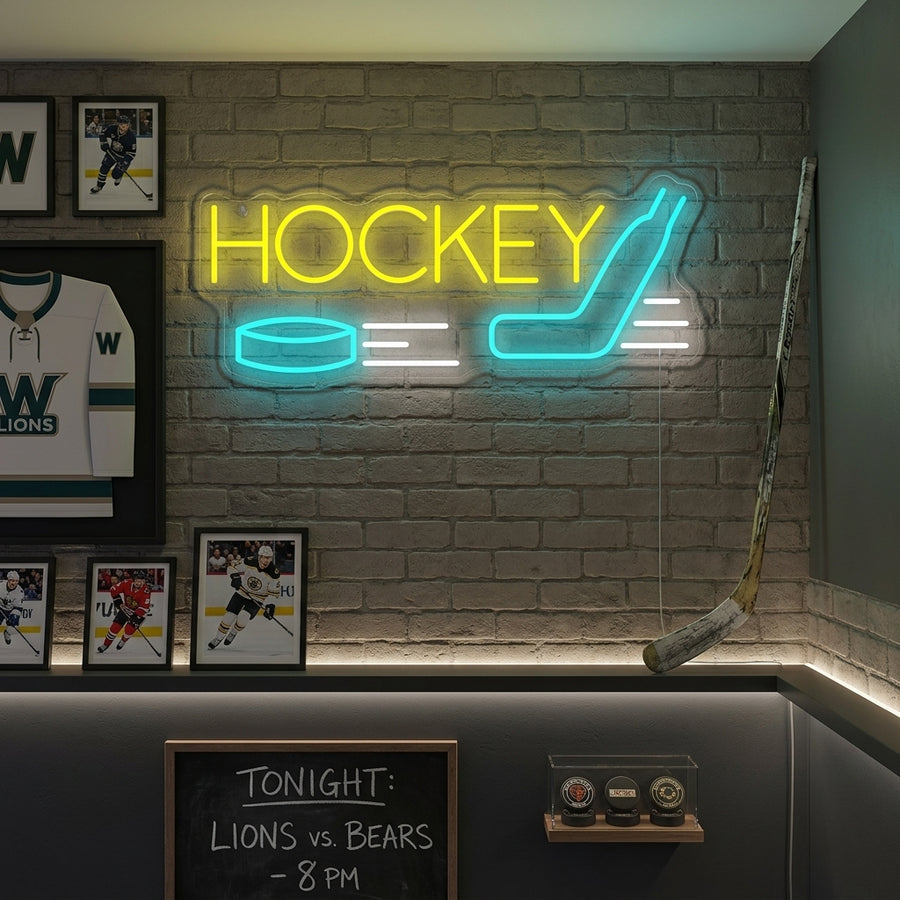 A hockey neon sign featuring an illuminated player figure in an action pose with stick and puck, glowing blue, against a backdrop of a brick wall and various hockey memorabilia in a well-lit room.