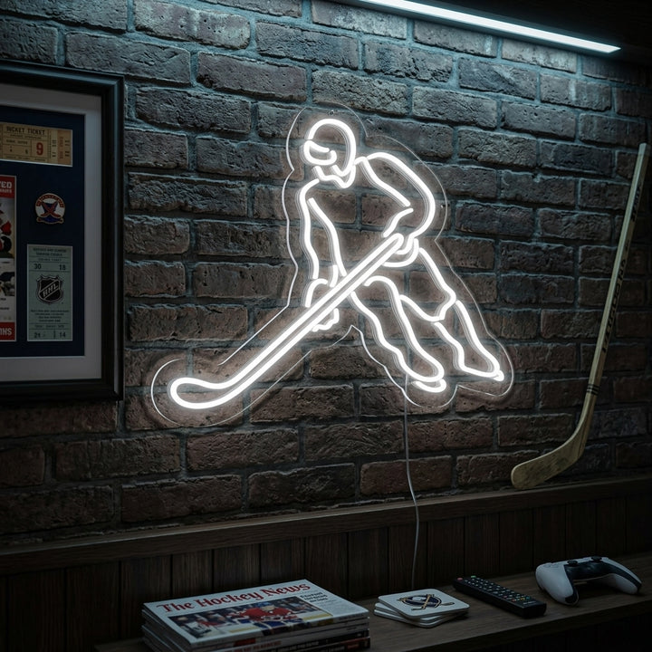 Illuminated neon sign depicting a dynamic hockey player figure in action, mounted on a brick wall in a cozy living room setting above a sofa.