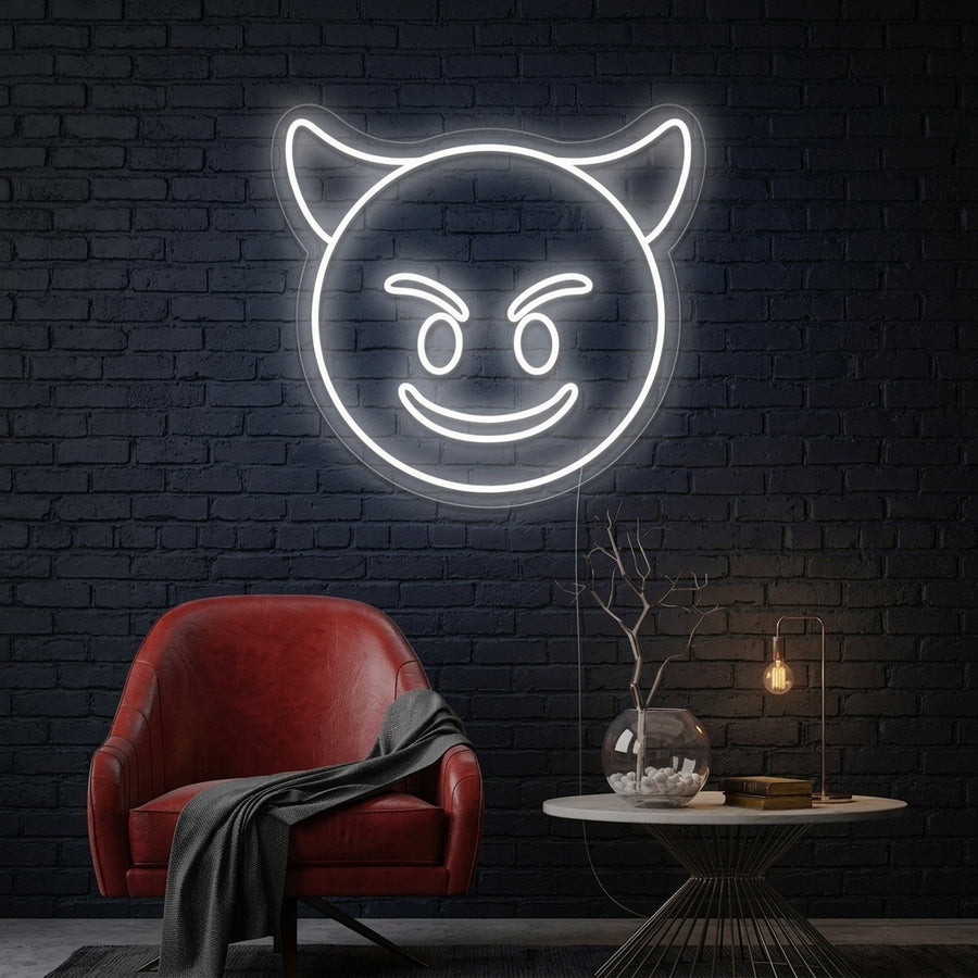 A wall-mounted, smirking purple Evil Emoji neon sign glowing above a dark leather sofa and coffee table in a modern loft environment.