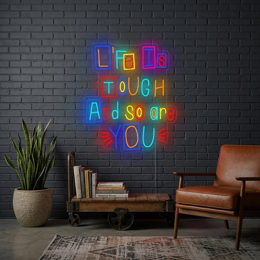 Motivational 'Life is Tough and So Are You' neon sign glowing on a stylish wall in a living room setting.