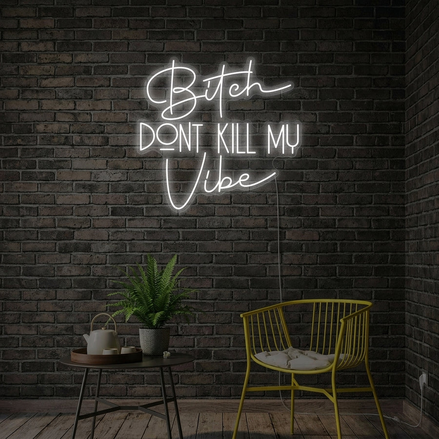 Bitch Dont Kill My Vibe neon sign glowing on a textured wall in a styled room.