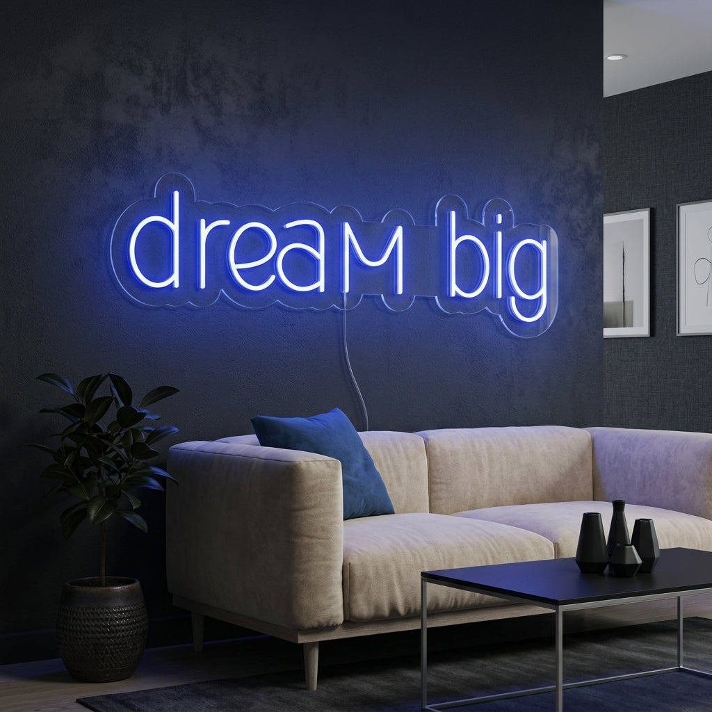 "Dream Big" neon sign glowing in white script on a minimalist home office wall above a stylish desk setup