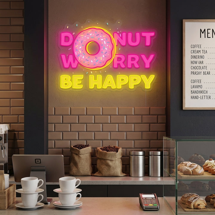 A cozy kitchen setting with the glowing 'Donut Do Not Worry Be Happy' neon sign mounted above a counter with pastries.