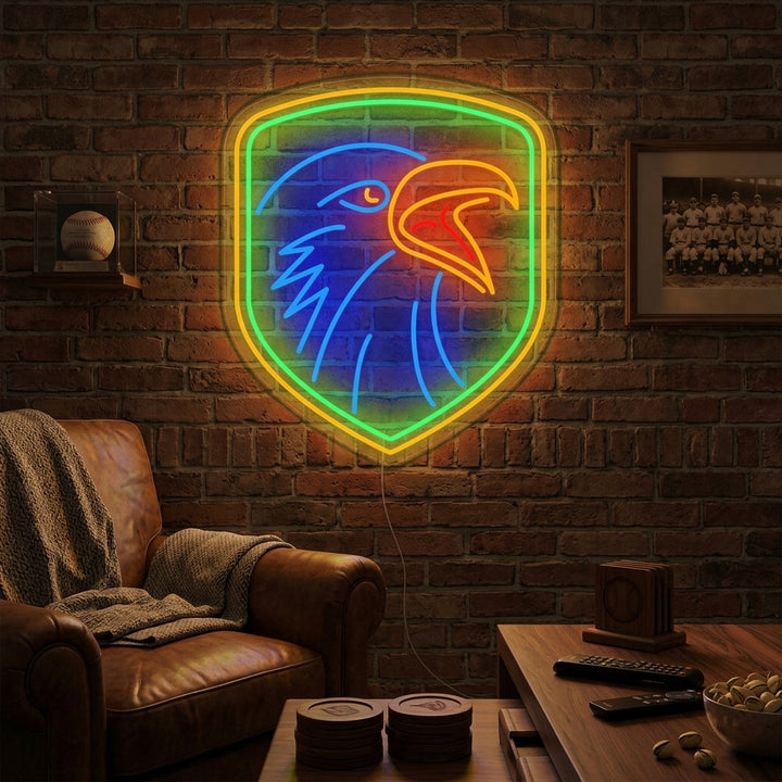 A glowing blue and yellow neon sign depicting an eagle with a shield on a brick wall in a rustic room.