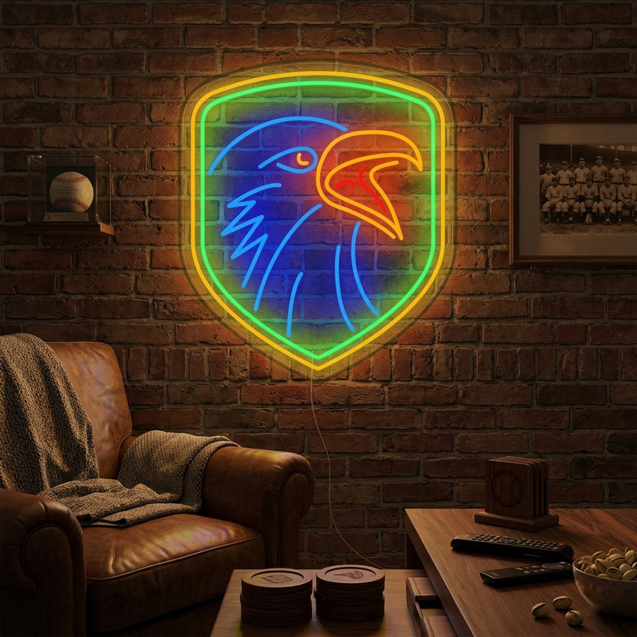 A glowing blue and yellow neon sign depicting an eagle with a shield on a brick wall in a rustic room.