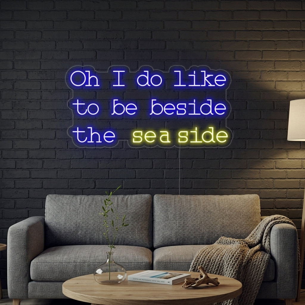 An illuminated 'Oh I do like to be beside the seaside' neon sign mounted on a textured wall in a bright, modern living room.