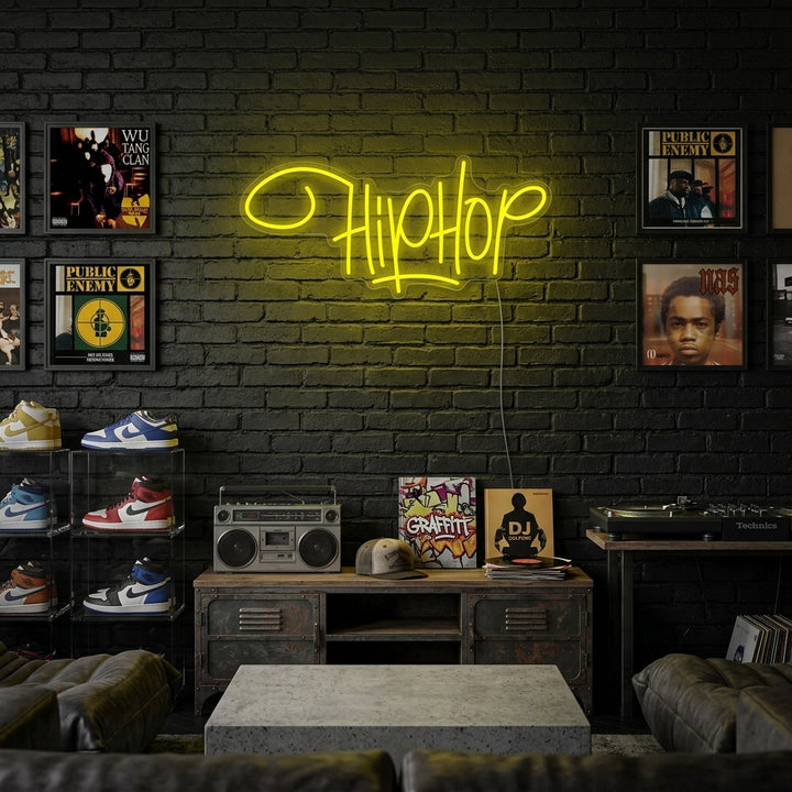 A glowing 'Hip Hop Rap Music' neon sign displayed on a dark brick wall in a lifestyle setting, illuminating a record player and urban decor.