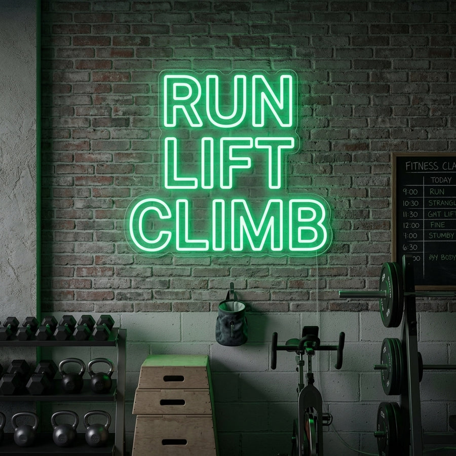 A Run Lift Climb Fitness neon sign, featuring icons for running, lifting, and climbing, glows with bright white light on a dark gym wall above workout equipment.