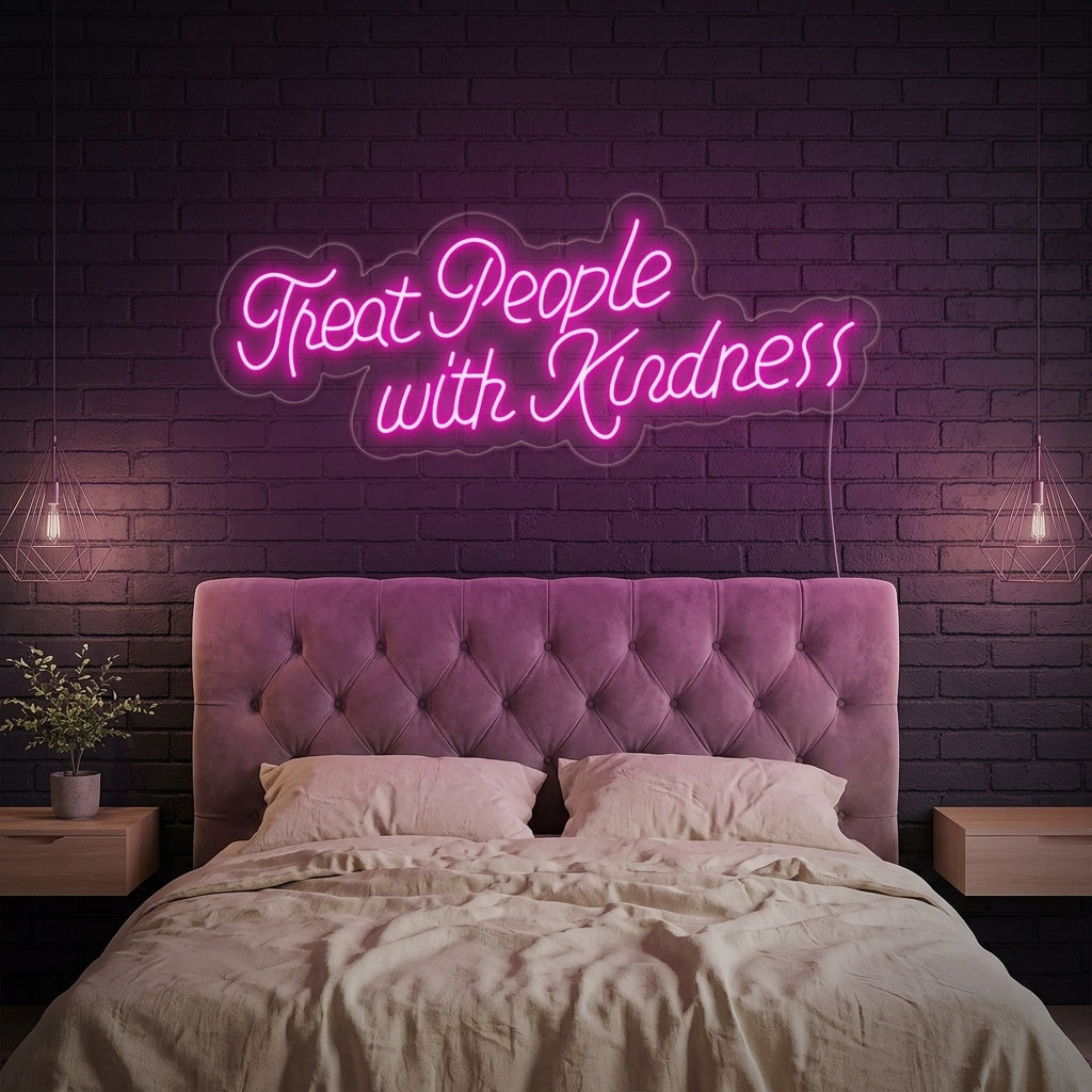 A vibrant Treat People With Kindness neon sign in glowing pink cursive, mounted on a wall above a modern desk setup in a stylish home office.
