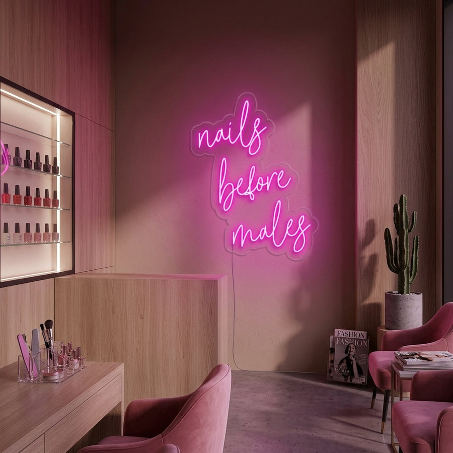 A glowing pink 'Nails Before Males' neon sign displayed prominently on a wall in a stylish nail salon setting.