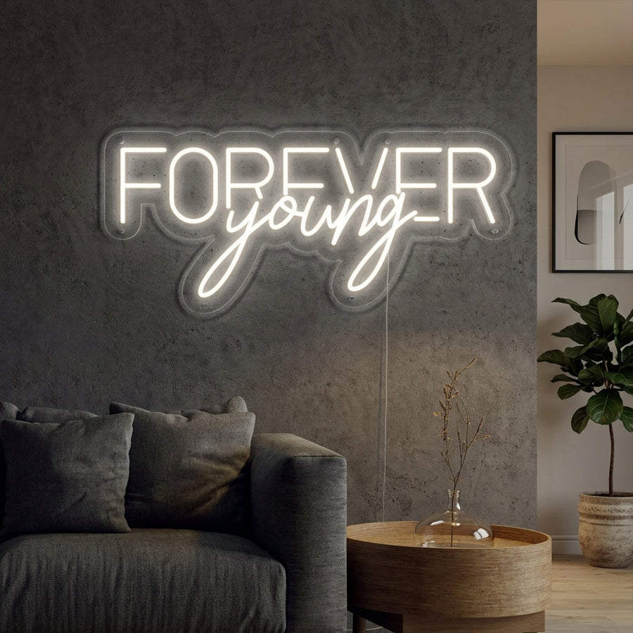 A vibrant 'Forever Young' neon sign mounted on a clean wall in a modern bedroom setting.