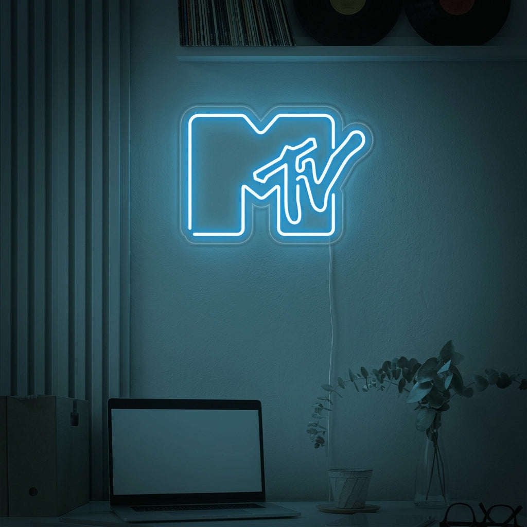 The iconic blocky M and stylized TV of the classic MTV logo, illuminated as a vibrant pink and orange neon sign mounted on a textured brick wall in a retro-style living room or studio space.