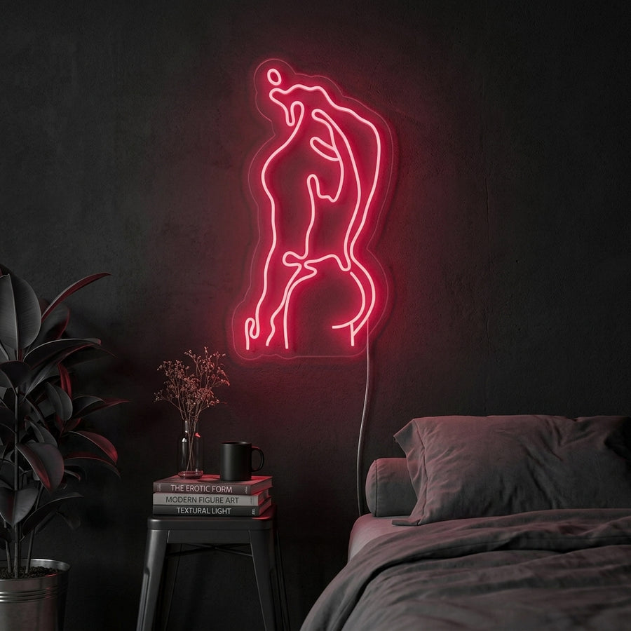 A vibrant red 'Strong Man Body Human Male Body' neon sign glowing on a textured brick wall above a gym weight rack, showcasing its fitness-focused appeal.
