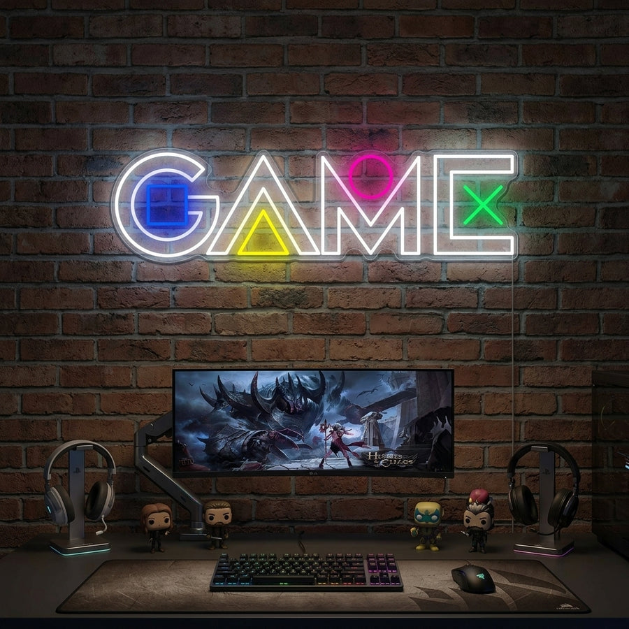 A vibrant 'GAME' neon sign glowing above a modern gaming desk setup in a dimly lit room.