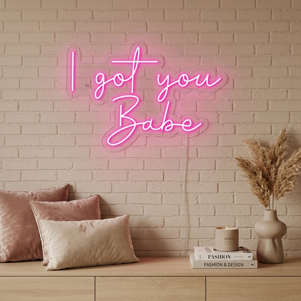 I Got You Babe script neon sign glowing warm pink over a decorated sofa with plants