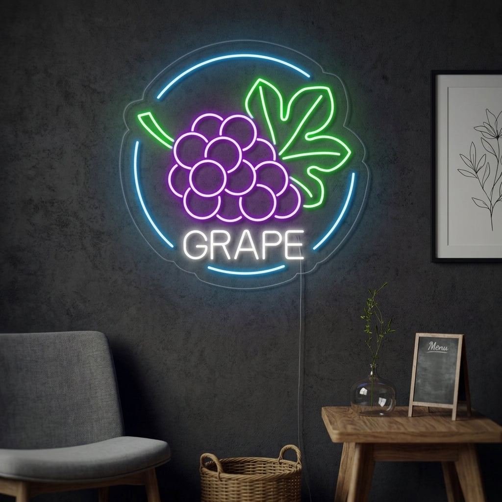 A glowing green neon sign depicting a bunch of grapes with leaves on a branch is mounted on a white wall. The sign emits a soft green light, illuminating the space, with a potted plant and a stack of books visible on a shelf below.