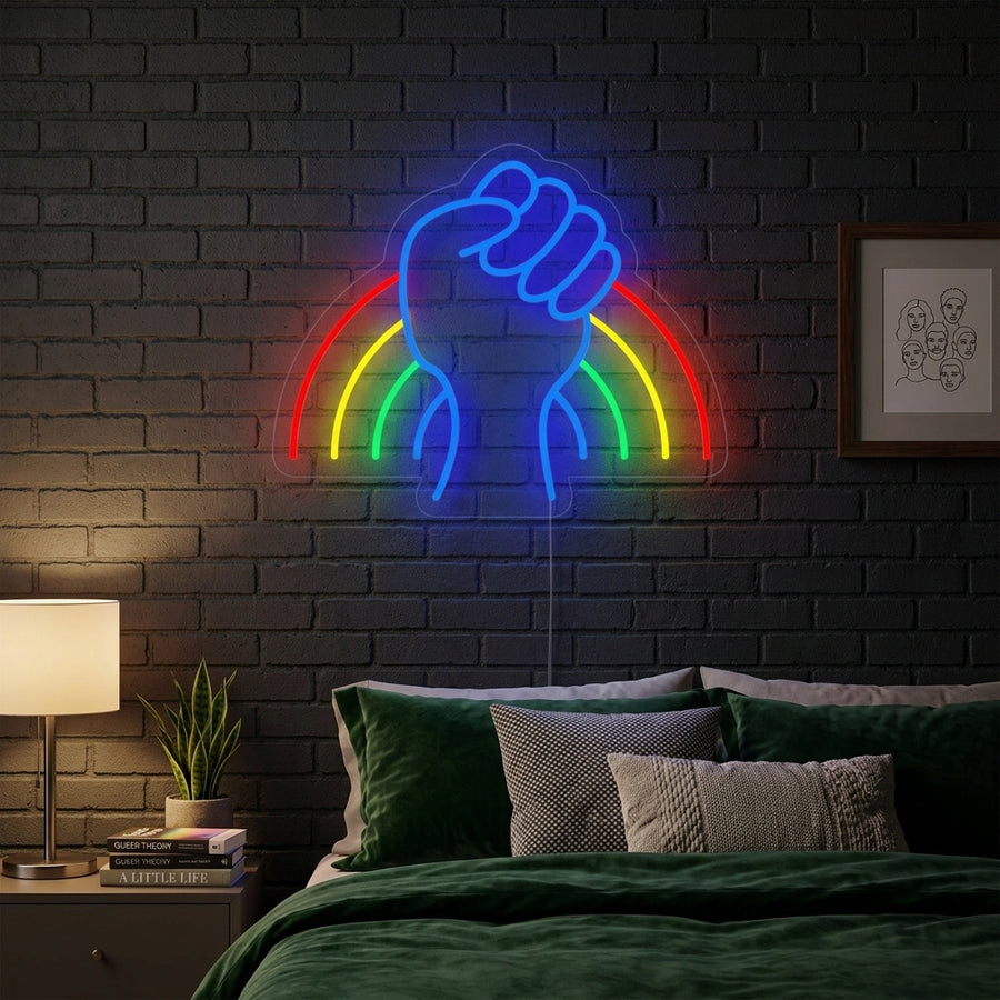 A vibrant 'LGBT Power Rainbow' neon sign illuminating a modern bedroom, casting colorful reflections on the wall and bedding.