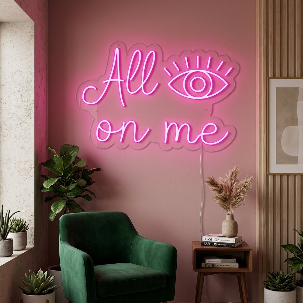 All Eyes On Me neon sign in script font glowing on a dark wall above a black velvet sofa in a modern living room setting.