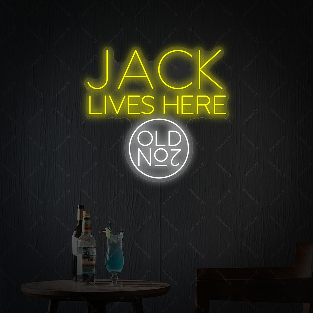 A bright Jack Lives Here and Jack Whiskey Neon Sign glowing in a dark, atmospheric home bar setting.