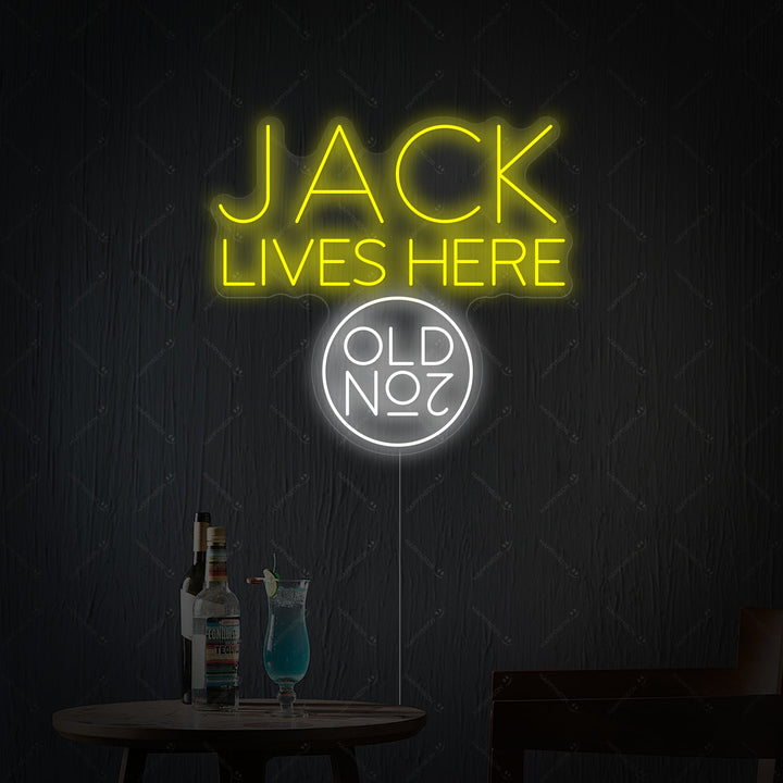 A bright Jack Lives Here and Jack Whiskey Neon Sign glowing in a dark, atmospheric home bar setting.