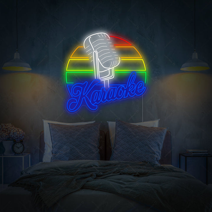 A colorful 'Karaoke' neon sign glowing above a bed in a modern bedroom, featuring a microphone icon and bold lettering against dark teal wall paneling.