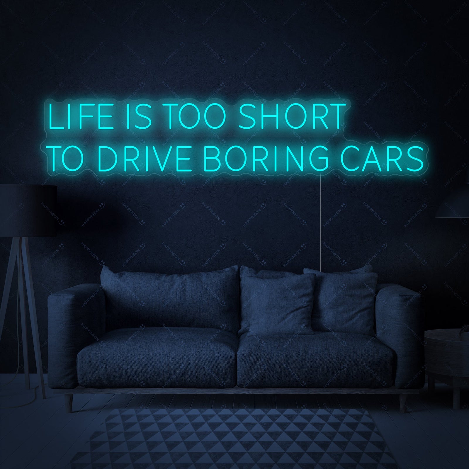 The 'Life Is Too Short To Drive Boring Cars' neon sign glowing above a modern grey sofa in a stylish living room environment.