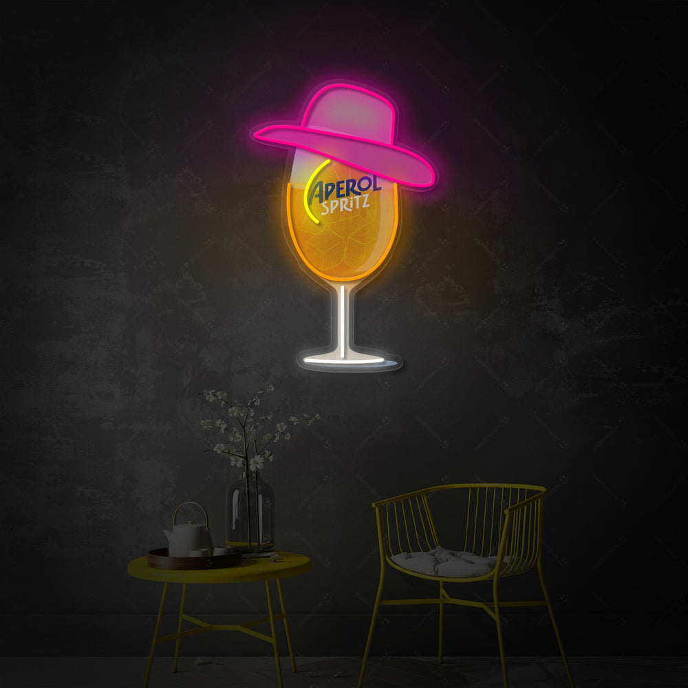 A close-up view of the Miss Aperol neon sign showing the orange glow and detailed script font mounted on a clear backboard.