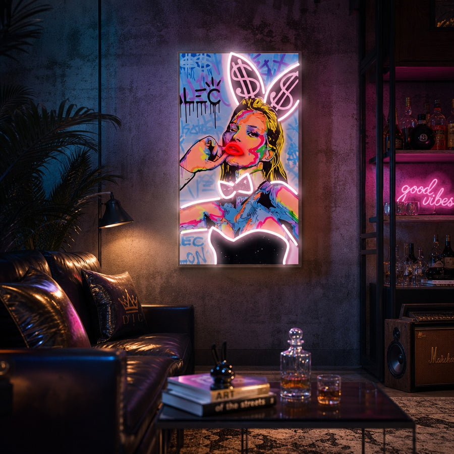 A lifestyle mockup showing the glowing Money Bunny neon sign on a cozy home office wall above a wooden desk with a laptop and plants, creating a modern pop art decor vibe.