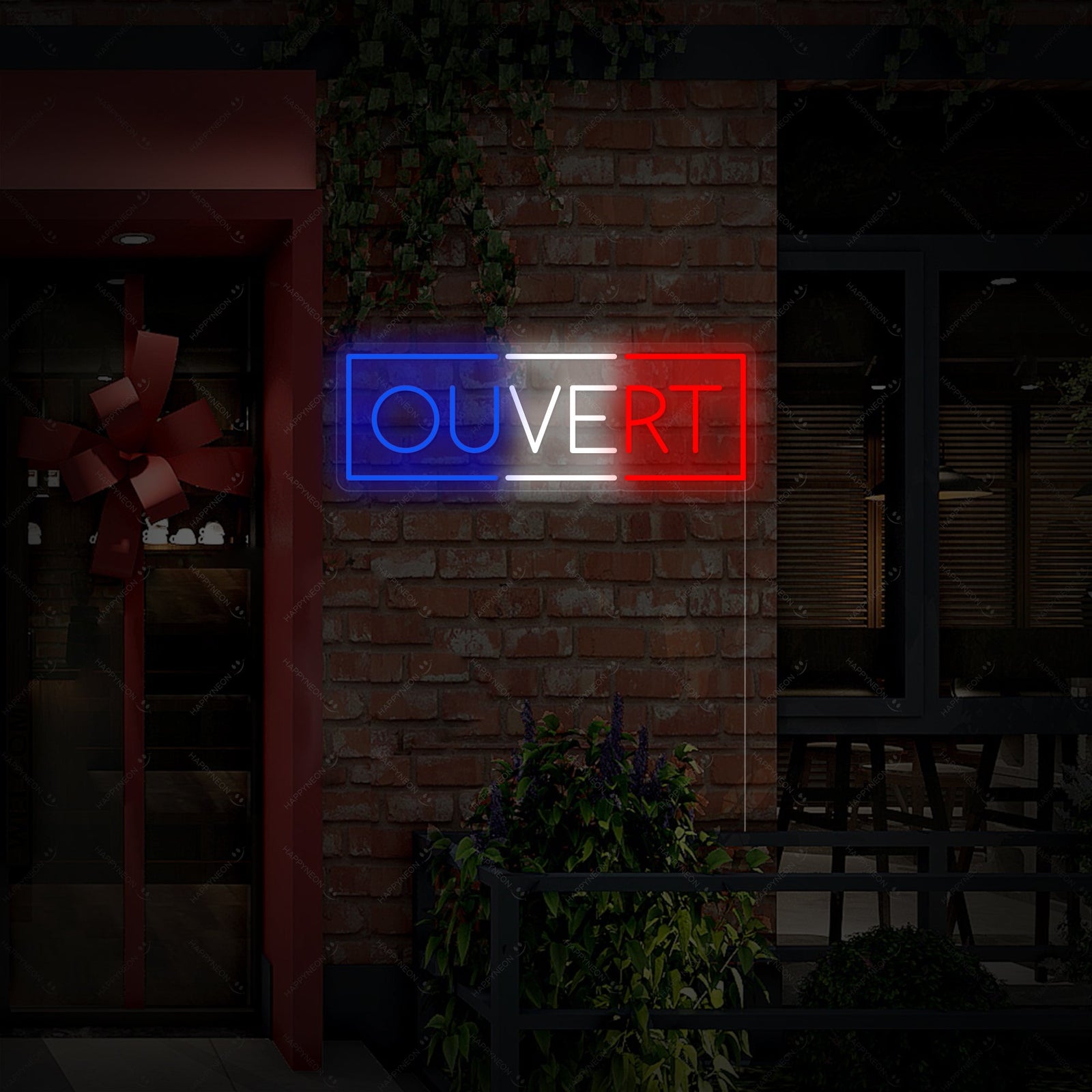 A realistic photograph of a custom 'Ouvert' neon sign with glowing tubing mounted on a clear acrylic backing, casting a pink glow on a wall inside a curated boutique window display. Multiple watermarks are visible across the image.