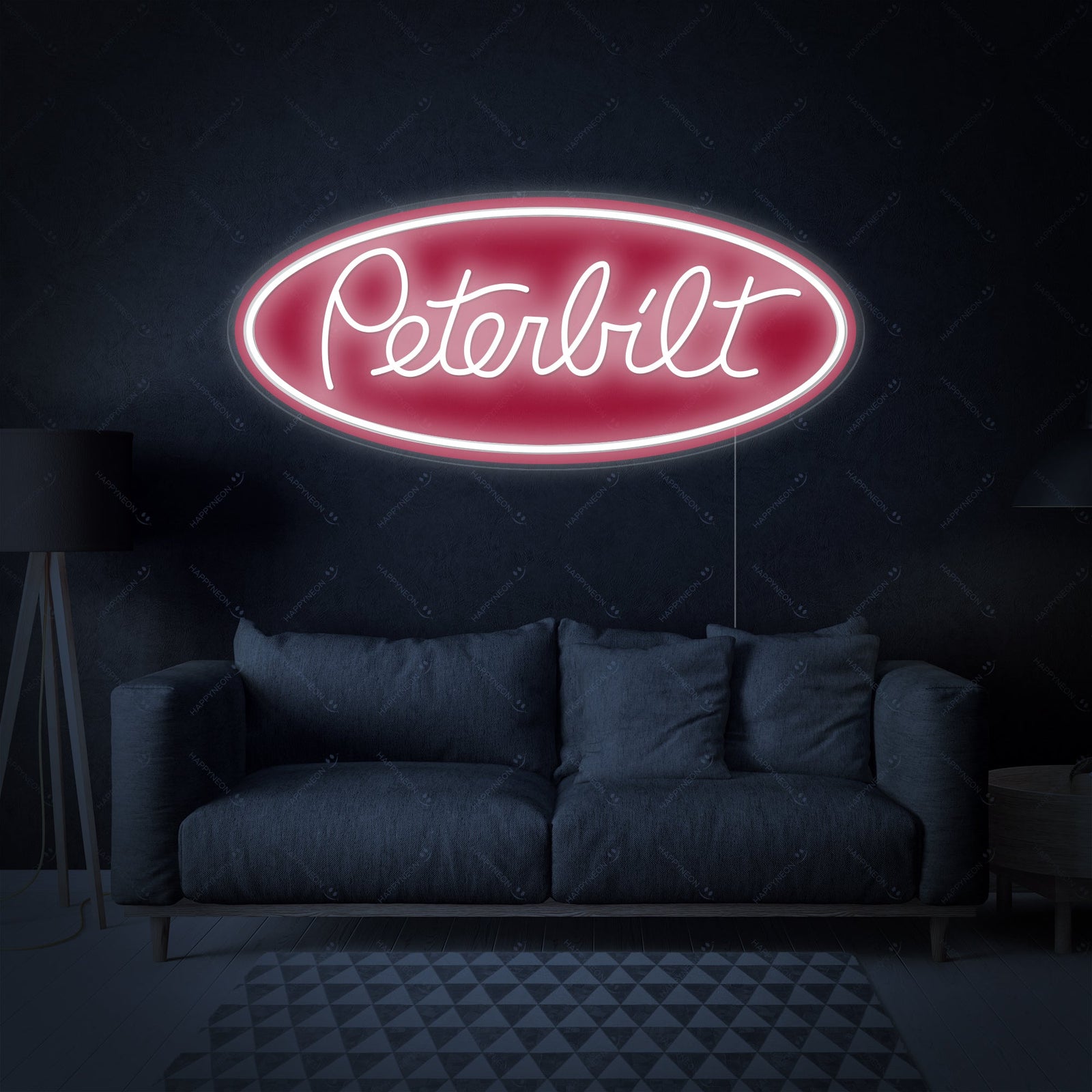 A glowing Peterbilt oval logo neon sign with red and white lighting, hanging above a workbench in a well-equipped automotive garage, showcasing detailed construction.