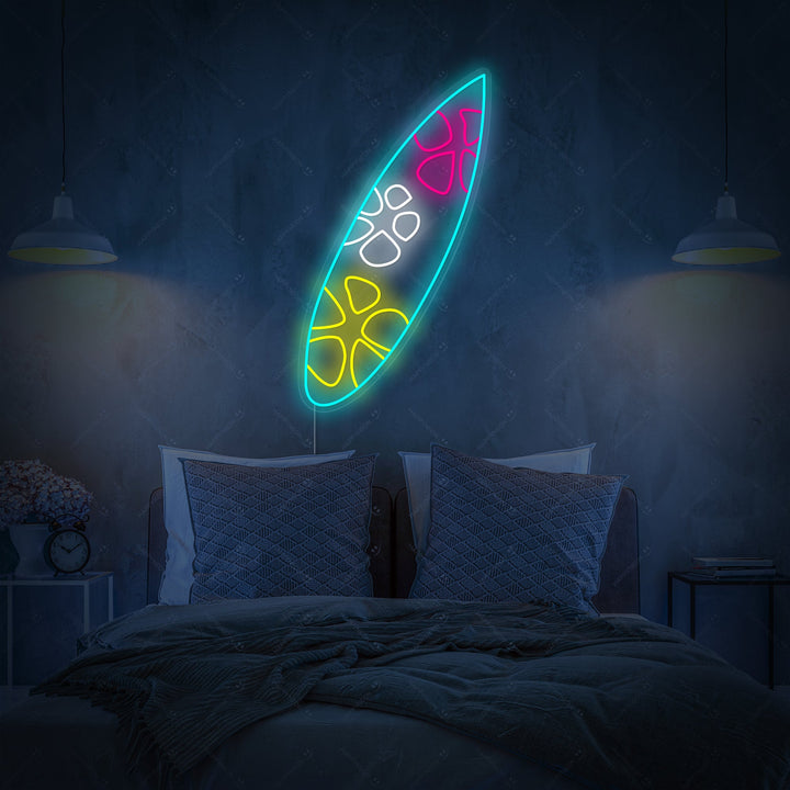 Close-up of a blue and white surfboard neon wall decor hanging above a rustic wooden bedside table.