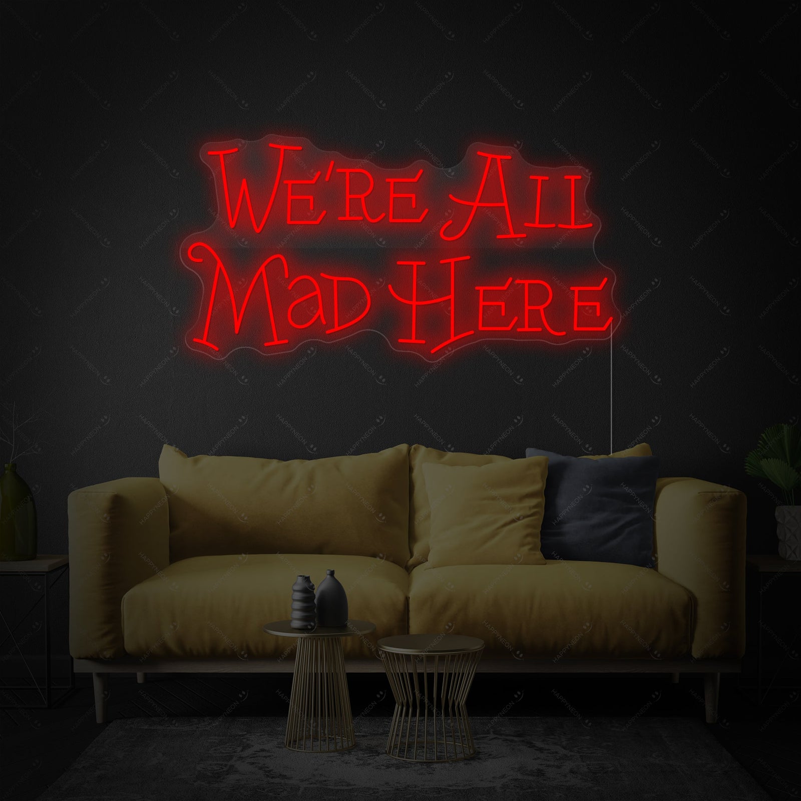 A clean, lit-up shot of the 'We're All Mad Here' neon sign with a playful Cheshire Cat grin design, mounted on a clear acrylic backing.
