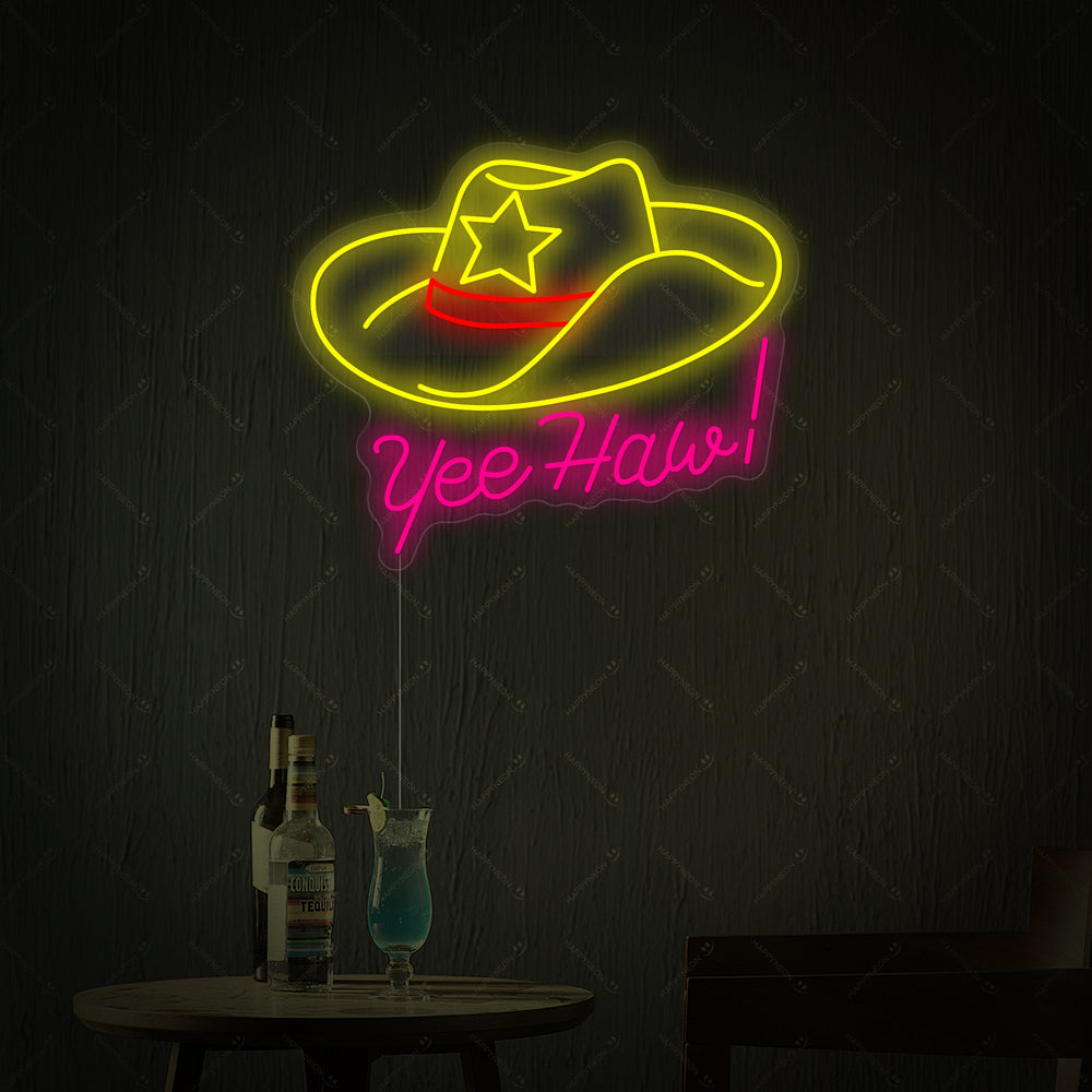 A digital rendering of the 'Yeehaw' neon sign showcasing its distinct neon tubing, an acrylic backboard, and a power cord, styled next to a table with drinks.