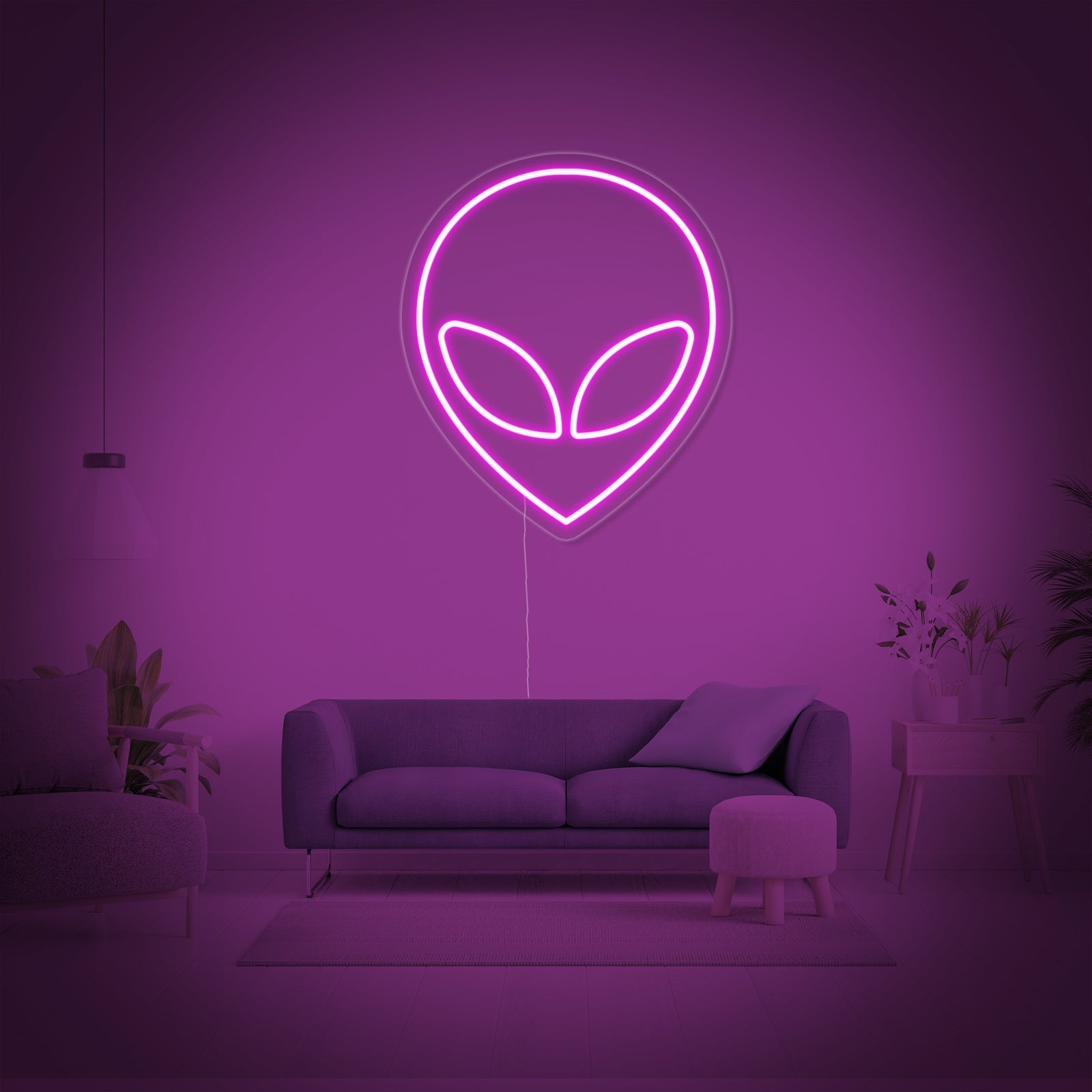 A bright green Alien neon sign showing an alien head, illuminating a modern room at night.