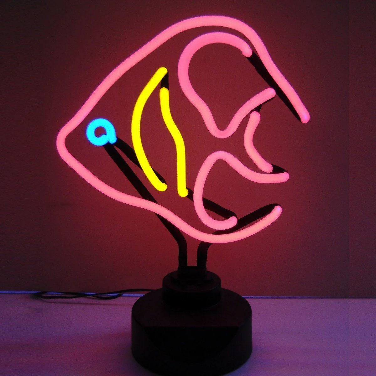 An 'Angelfish' table neon sign glowing with colorful light, featuring glass tube bends and a physical black base with a power cord, sitting on a desk.