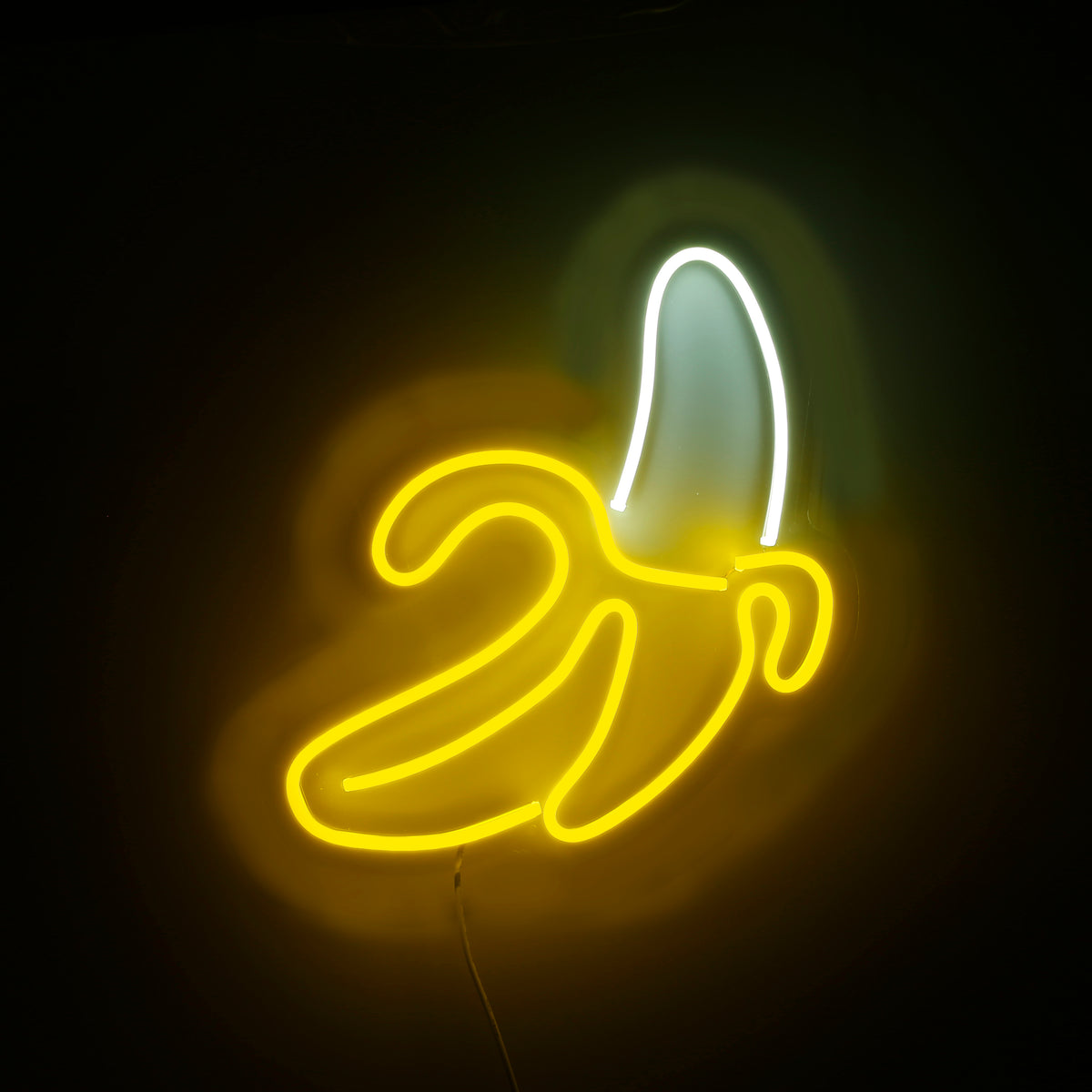 Banana shape neon sign glowing yellow on a dark wall