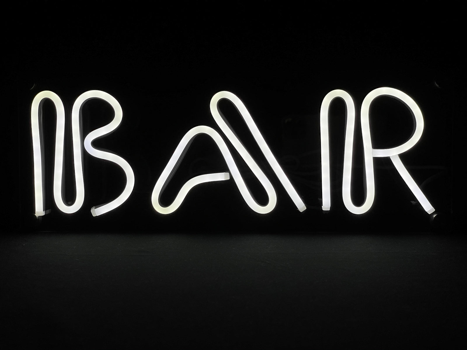 Glowing green "Bar" neon sign against a dark background.