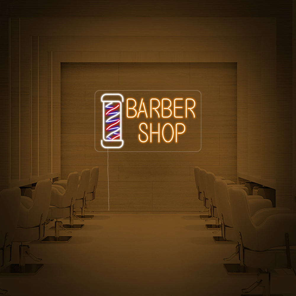 A close-up photograph of the 'Barber Shop' neon sign showcasing the detailed craftsmanship, glowing neon tubes, and clear mounting backboard against a stylish interior background.
