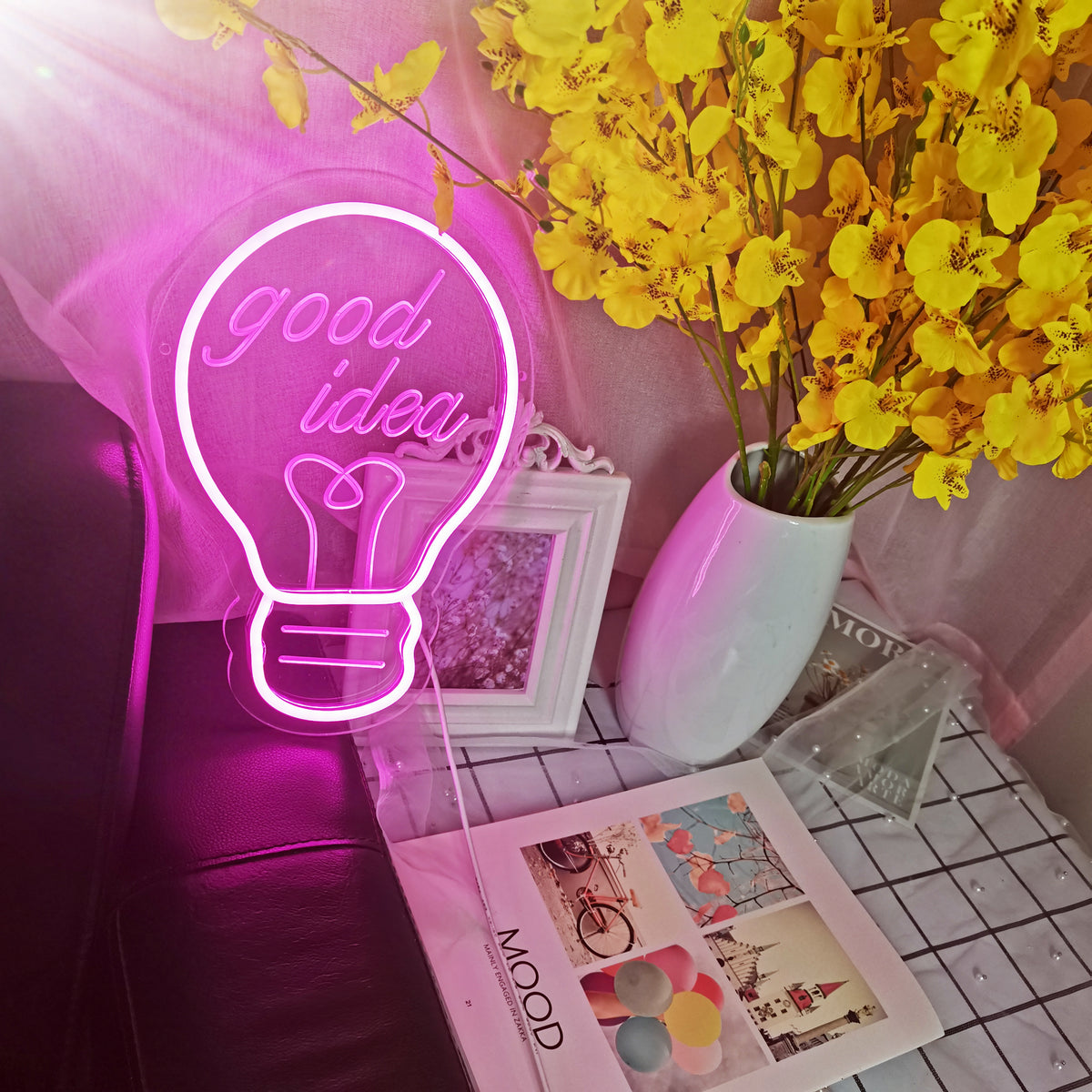 A close-up shot of the physically fabricated 'Bulb Good Idea' neon sign displaying bright, glowing tubes and a clear acrylic backing against a dark texture.