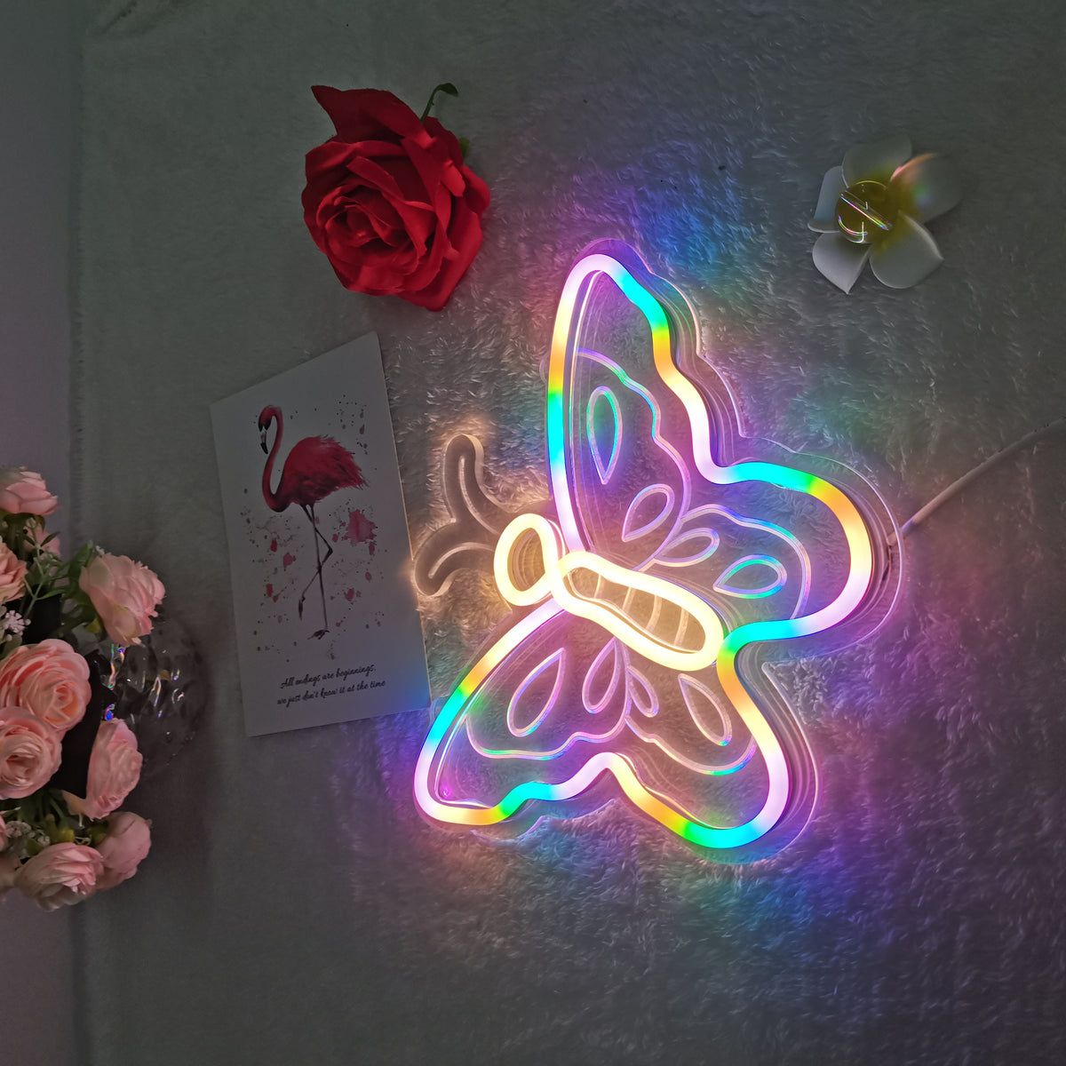 A glowing blue butterfly neon sign with a clear acrylic back, displayed against a light wooden wall.