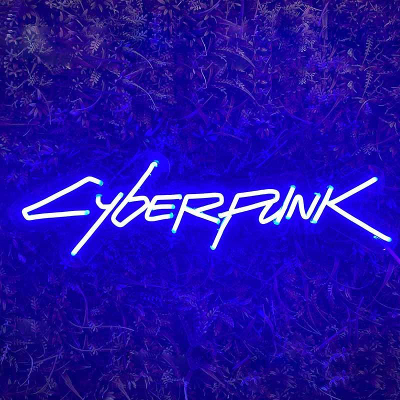 Close-up of CYBERPUNK neon sign mounted on a textured moss wall decor background.
