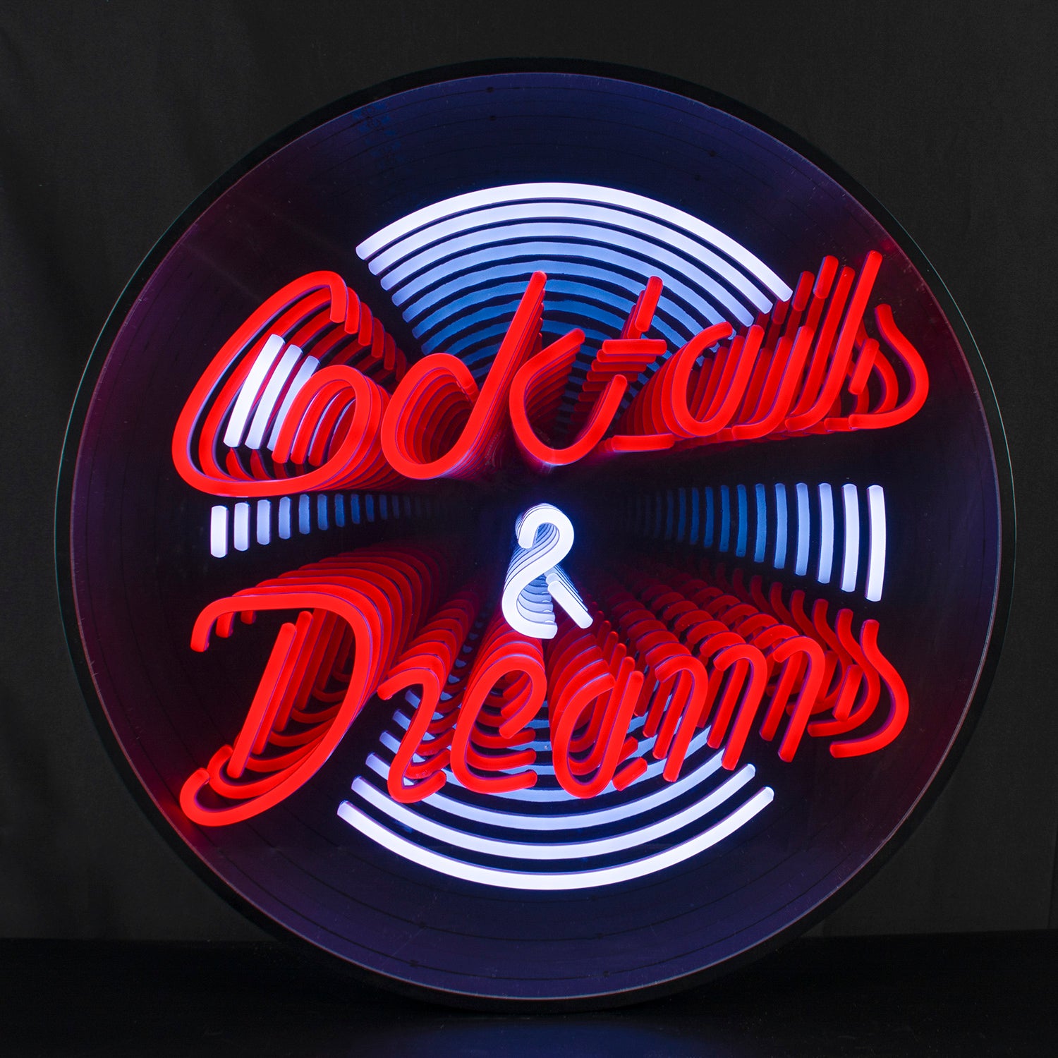 Photograph of the Cocktails Dreams 3D infinity neon sign showing recursive reflections in a dark setting.