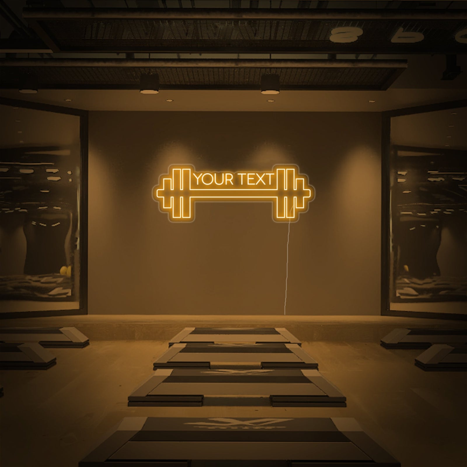 Custom gym logo or text illuminated as a neon sign hanging above racks of dumbbells and exercise equipment in a busy fitness center.