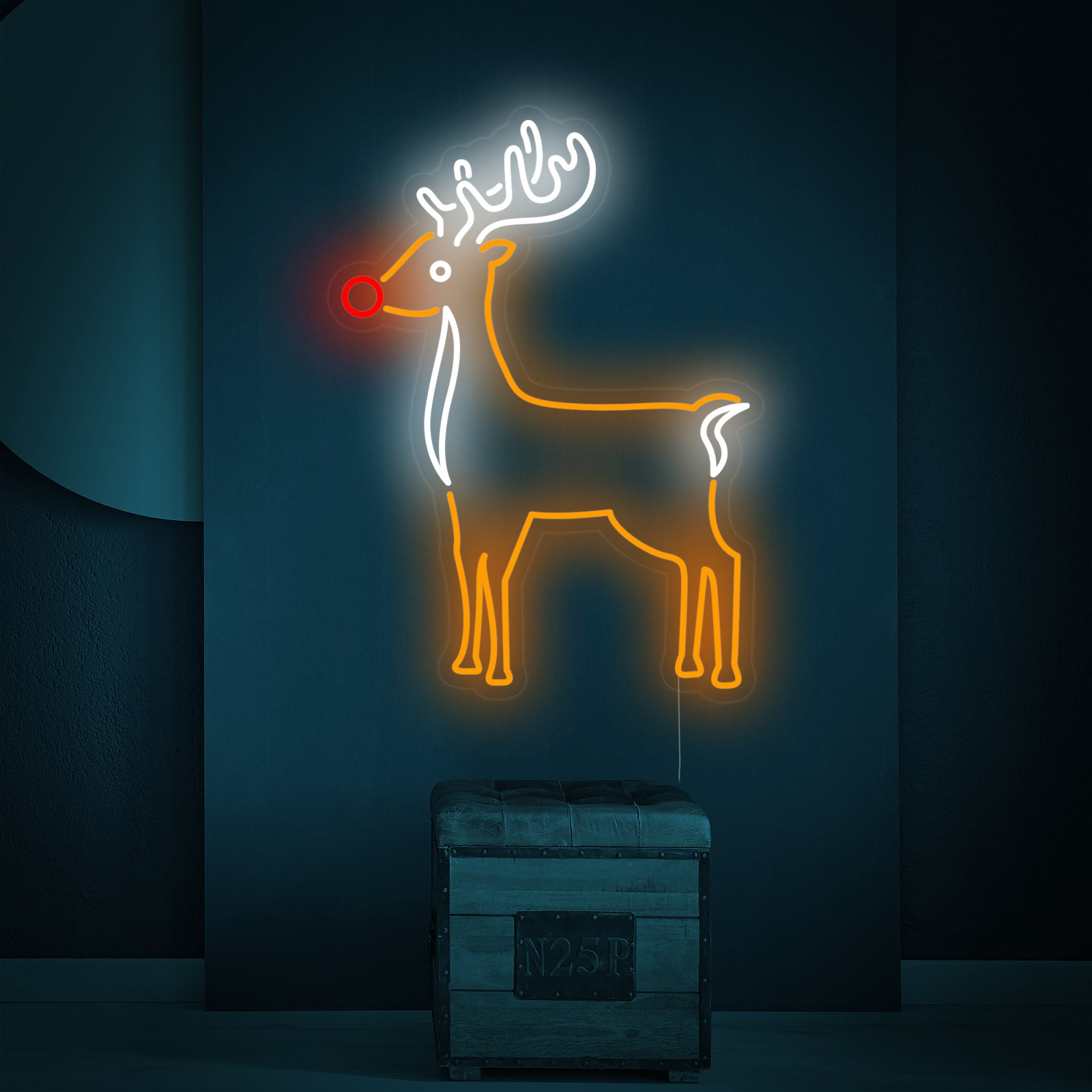 A lifestyle shot of the Cute Reindeer neon sign casting a colorful light in a dim room, leaning casually on an industrial-style stool against a textured wall.