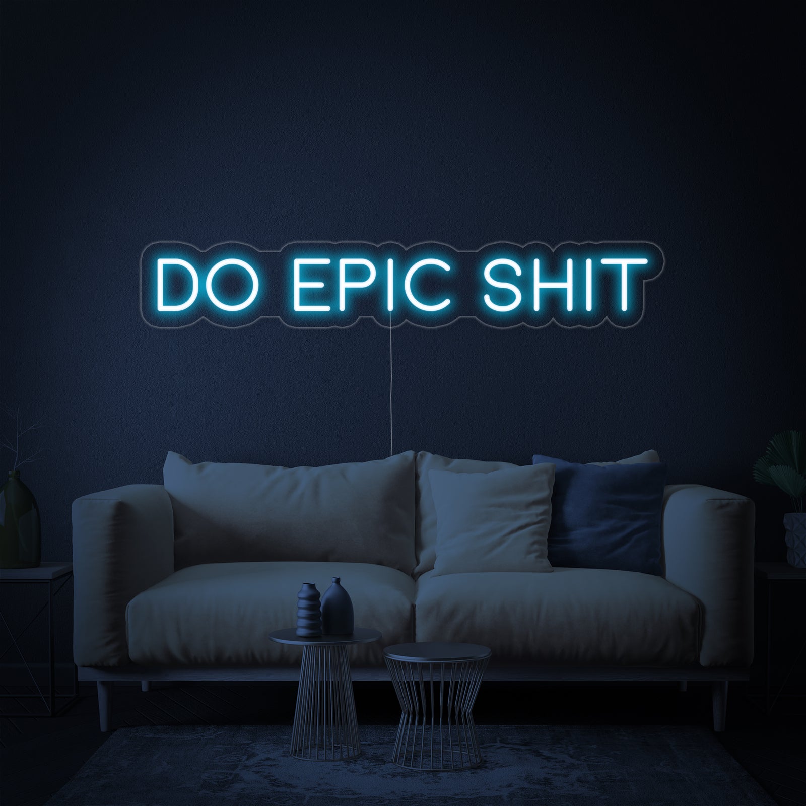 A modern interior setting featuring a glowing blue 'Do Epic Shit' neon sign displayed prominently on a textured wall above a clean, minimalist workspace.
