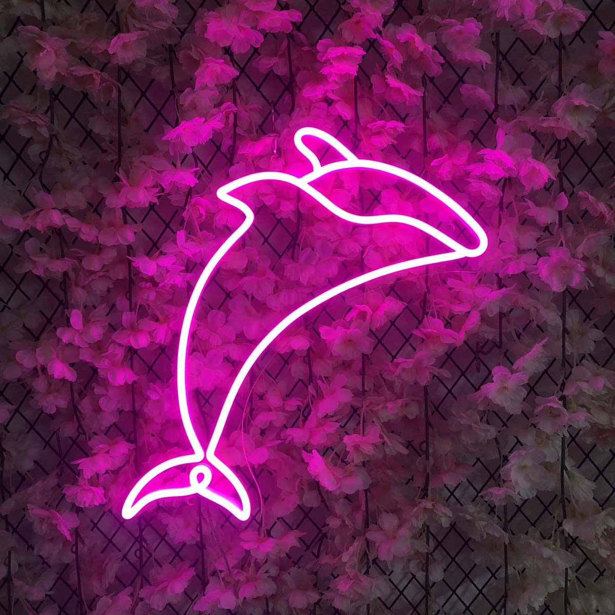 A glowing blue Dolphin Neon Sign mounted on a textured wall in a stylish living room setting.