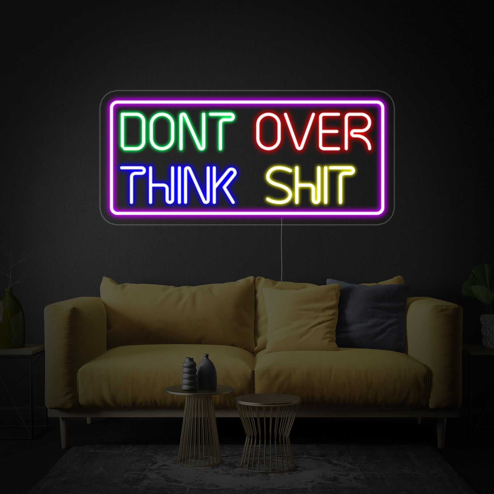 A glowing 'Dont Over Think Shit' neon sign rendered in handwritten script against a plain dark wall background.