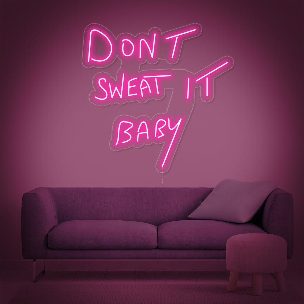 Stylized product view of the 'Dont Sweat it Baby' neon sign against a neutral wall.
